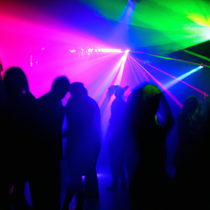 dance club with people dancing in silhouette with rainbow colored lighting
